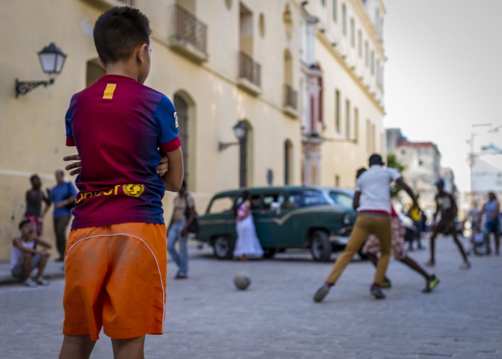 A group of boys playing soccer in the street