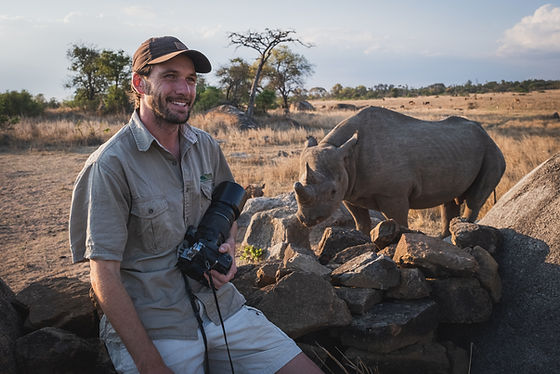 Sam Turley sittting next to a rhino