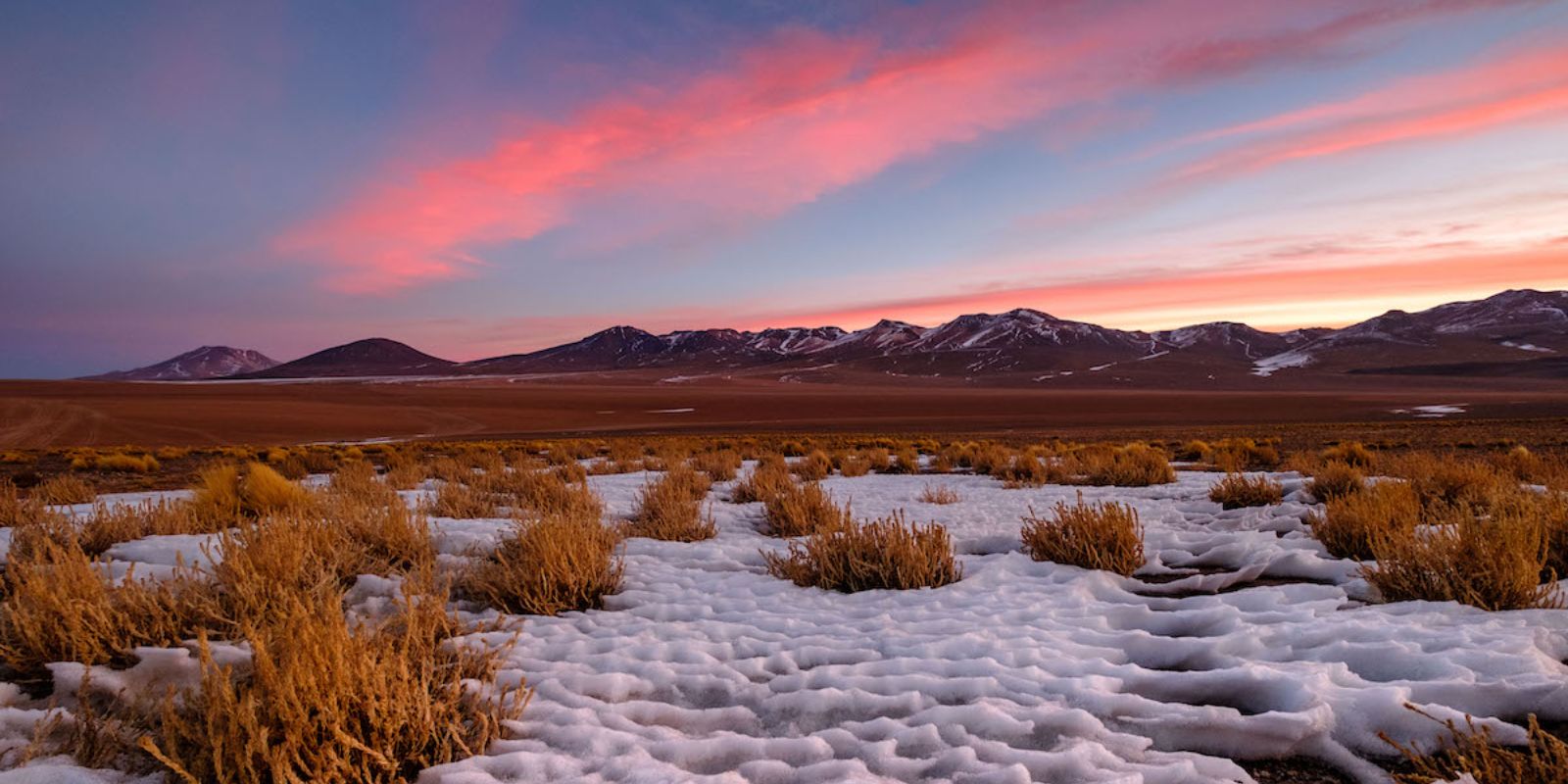a sunset over a snowy landscape with mountains in the background_5