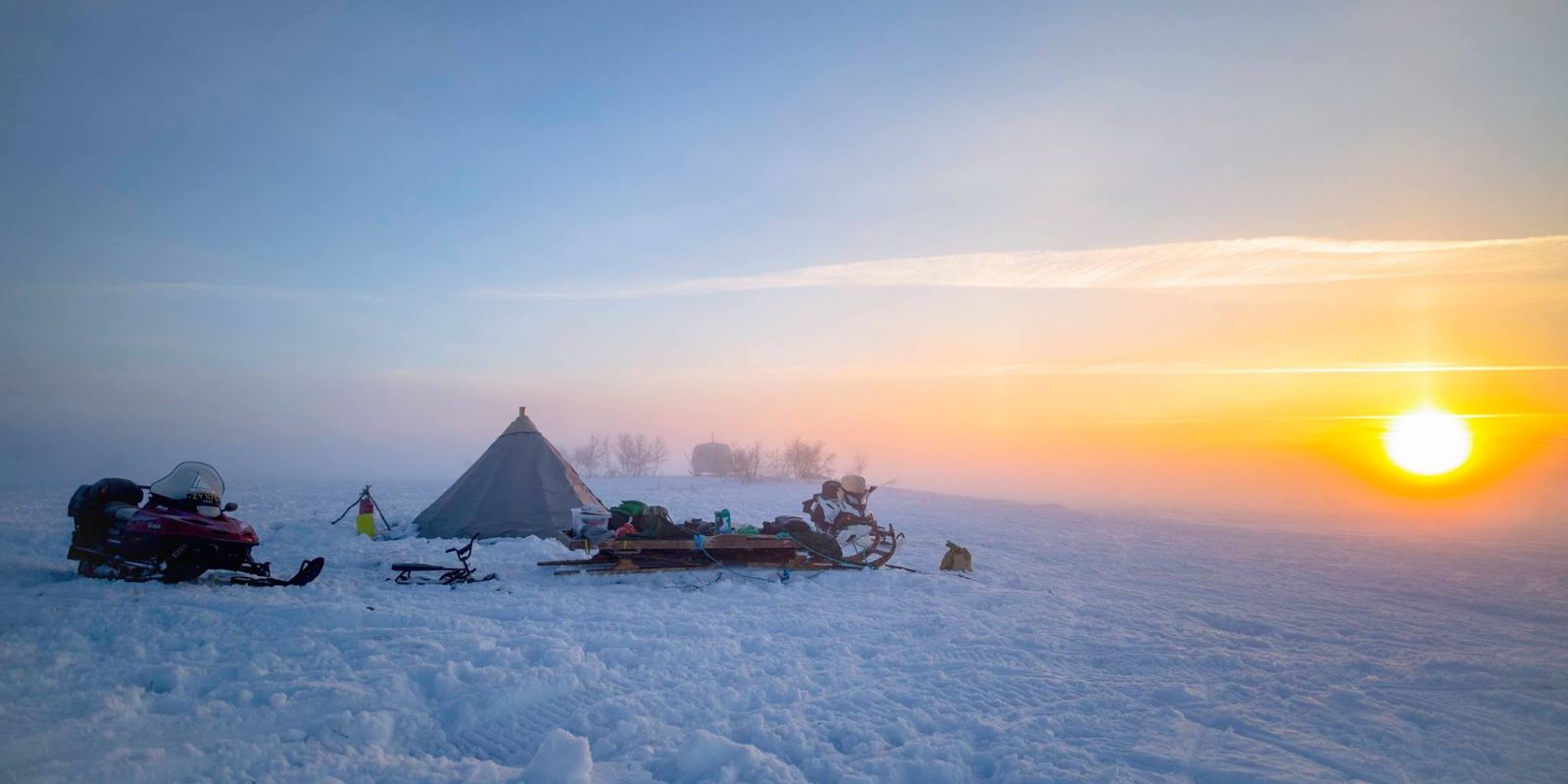 a group of people are camping in the snow with a tent in the background