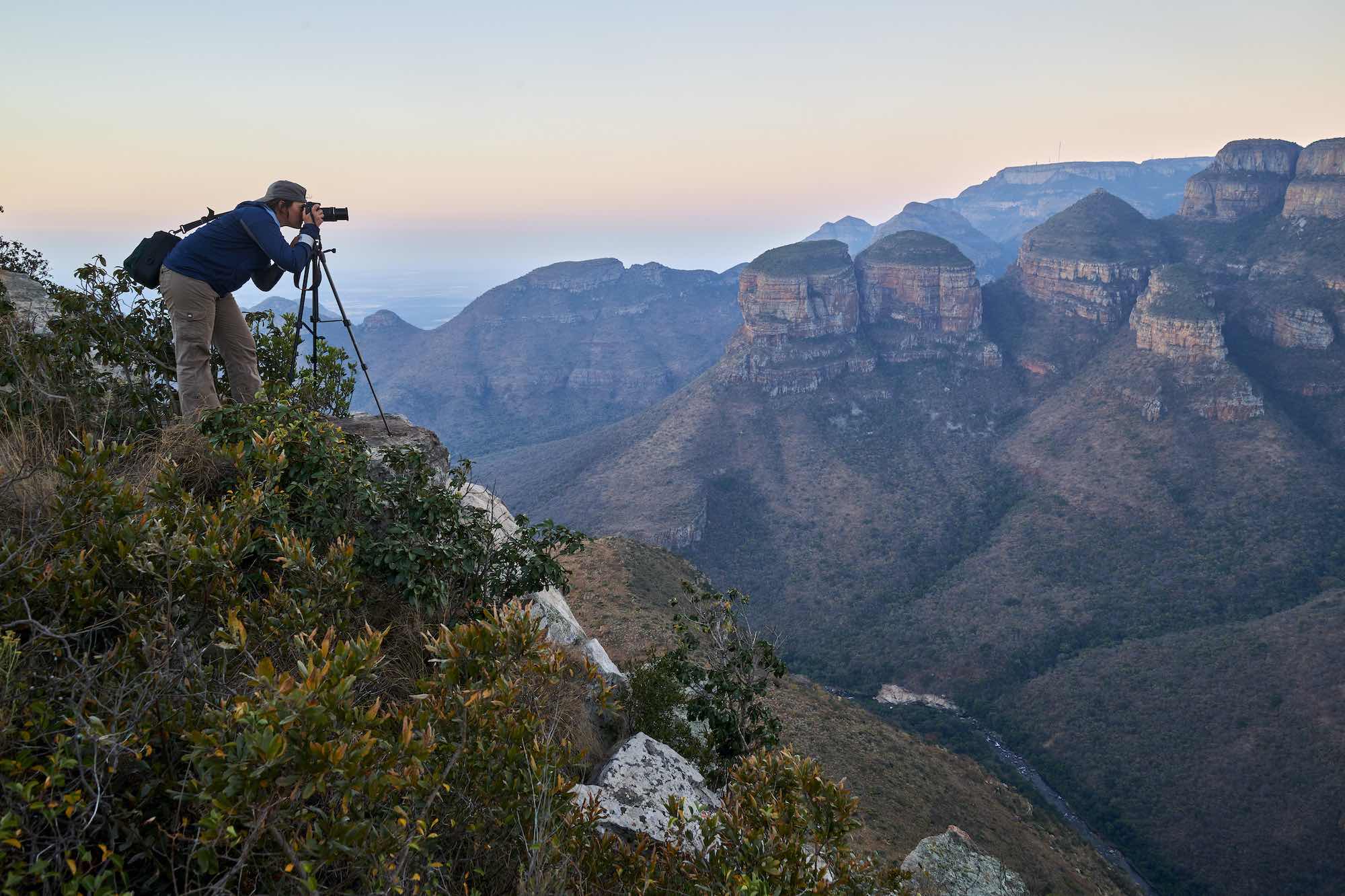 a photographer on top of a mountain taking a photo of the Blyde River Canyon