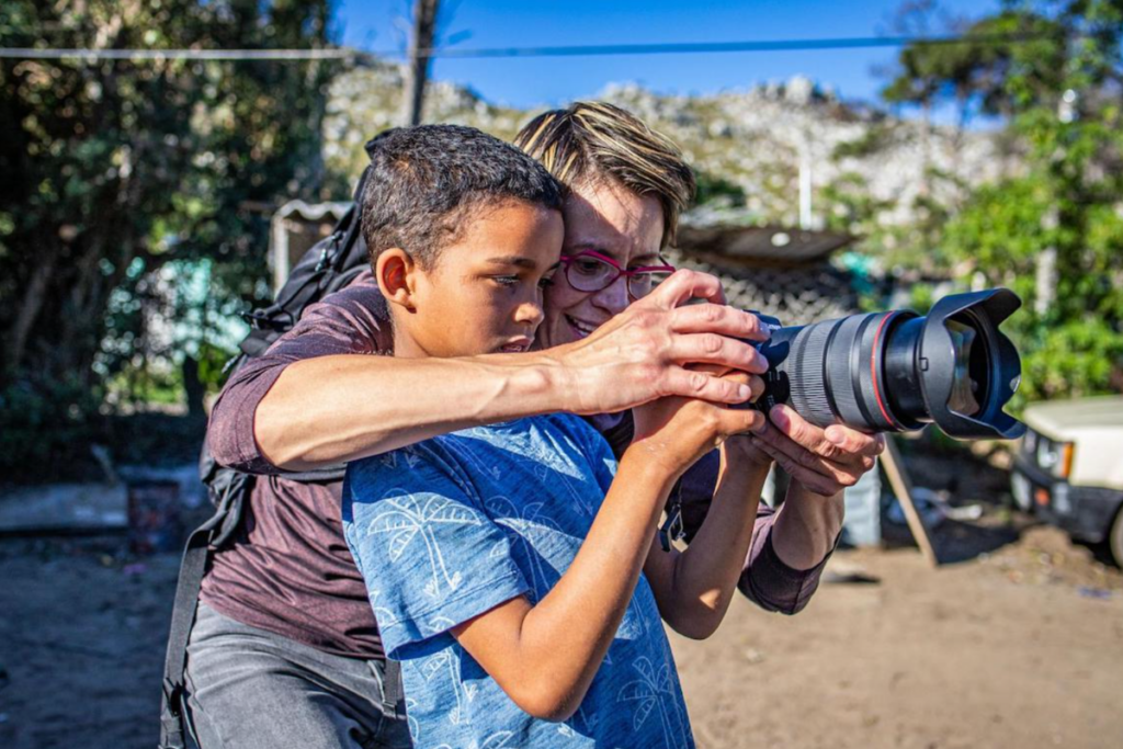 photo of a photogpraher teaching a child in africa how to use her camera