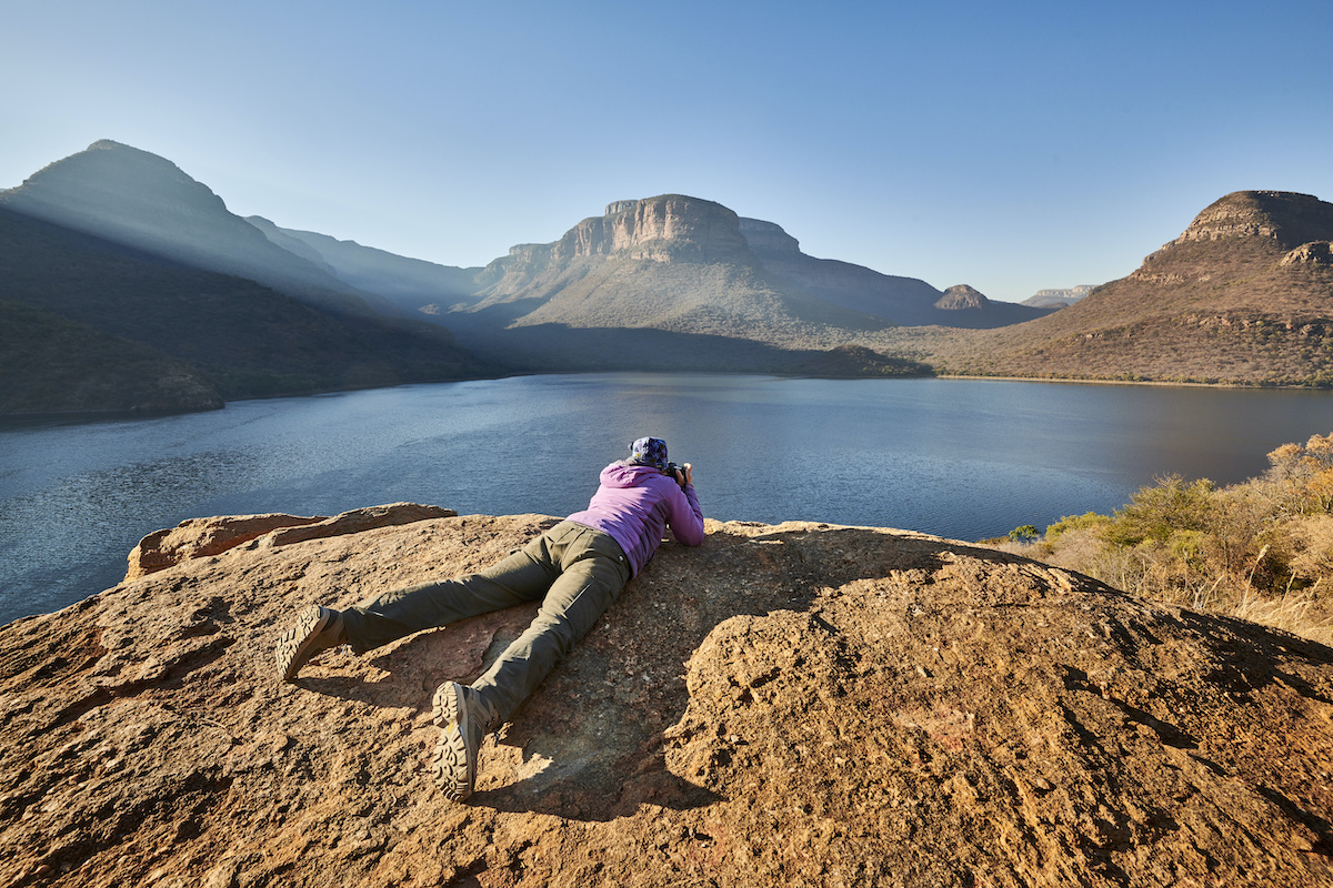 A person capturing a stunning photo of a serene mountain lake.