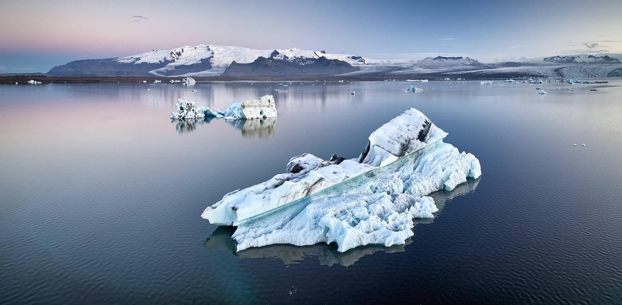 Icebergs floating on a calm glacial lagoon at sunset
