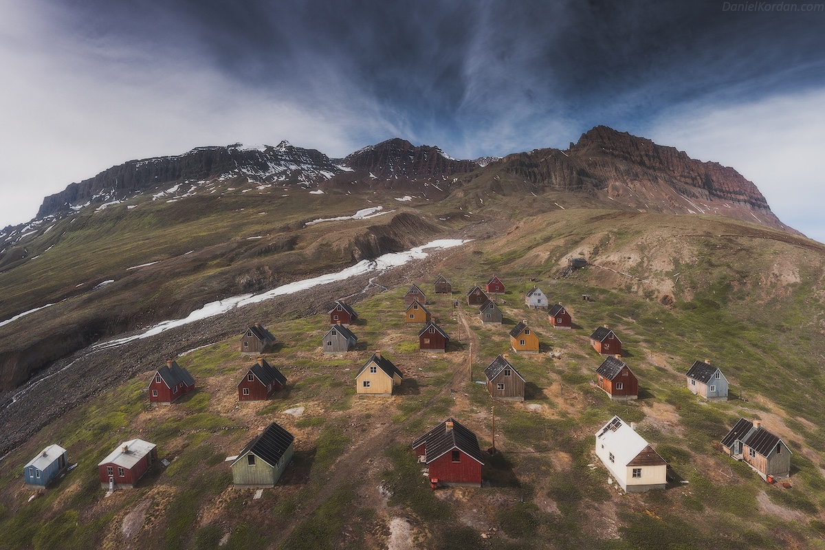 Remote village with colorful cabins in a mountain valley with patches of snow