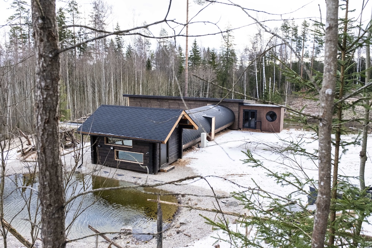 A modern wooden building in a snowy forest clearing