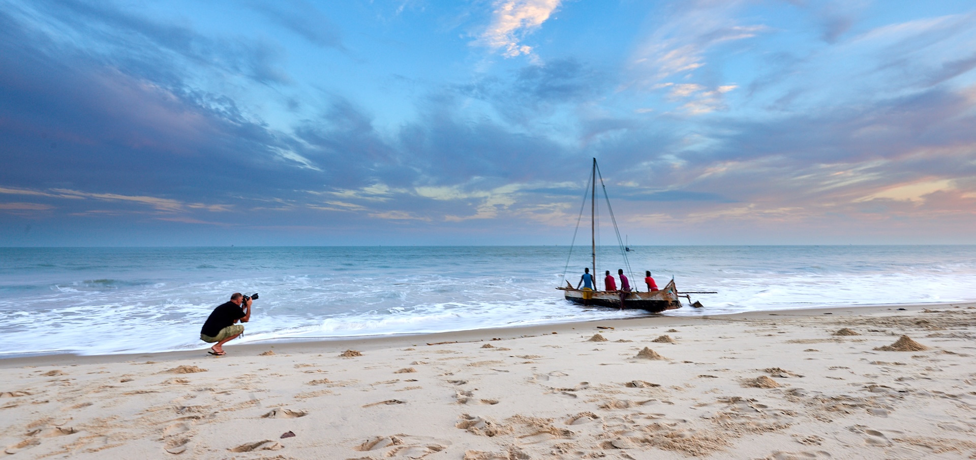 Person taking a photo of a boat on the beach