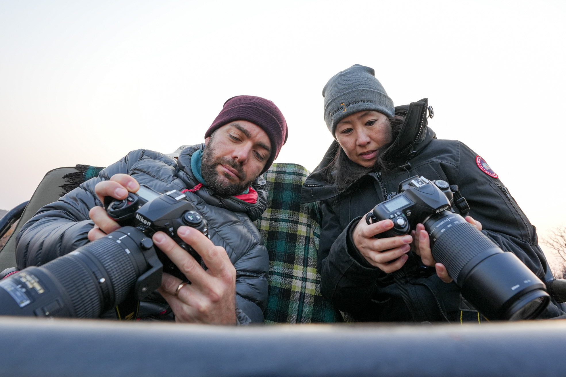 Two people sitting and looking at their cameras