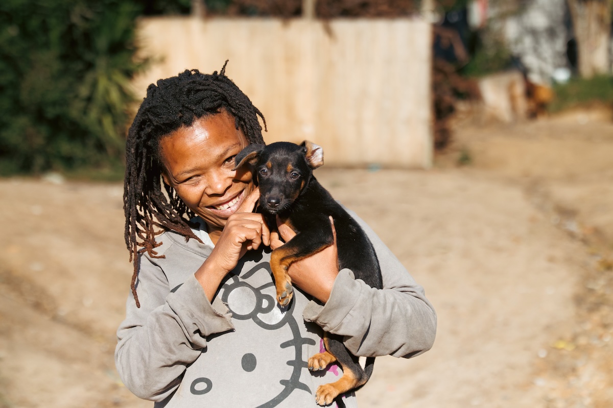Woman smiling while holding a small puppy