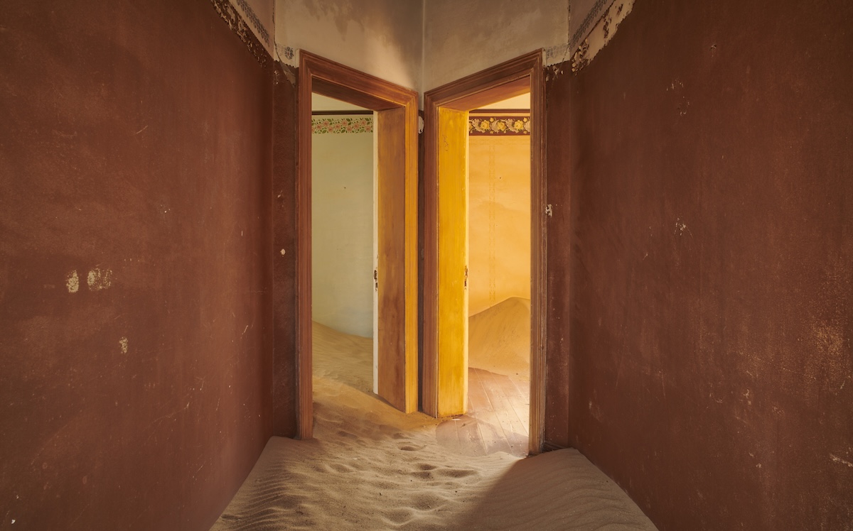 Interior hallway with red walls leading to sand-filled rooms