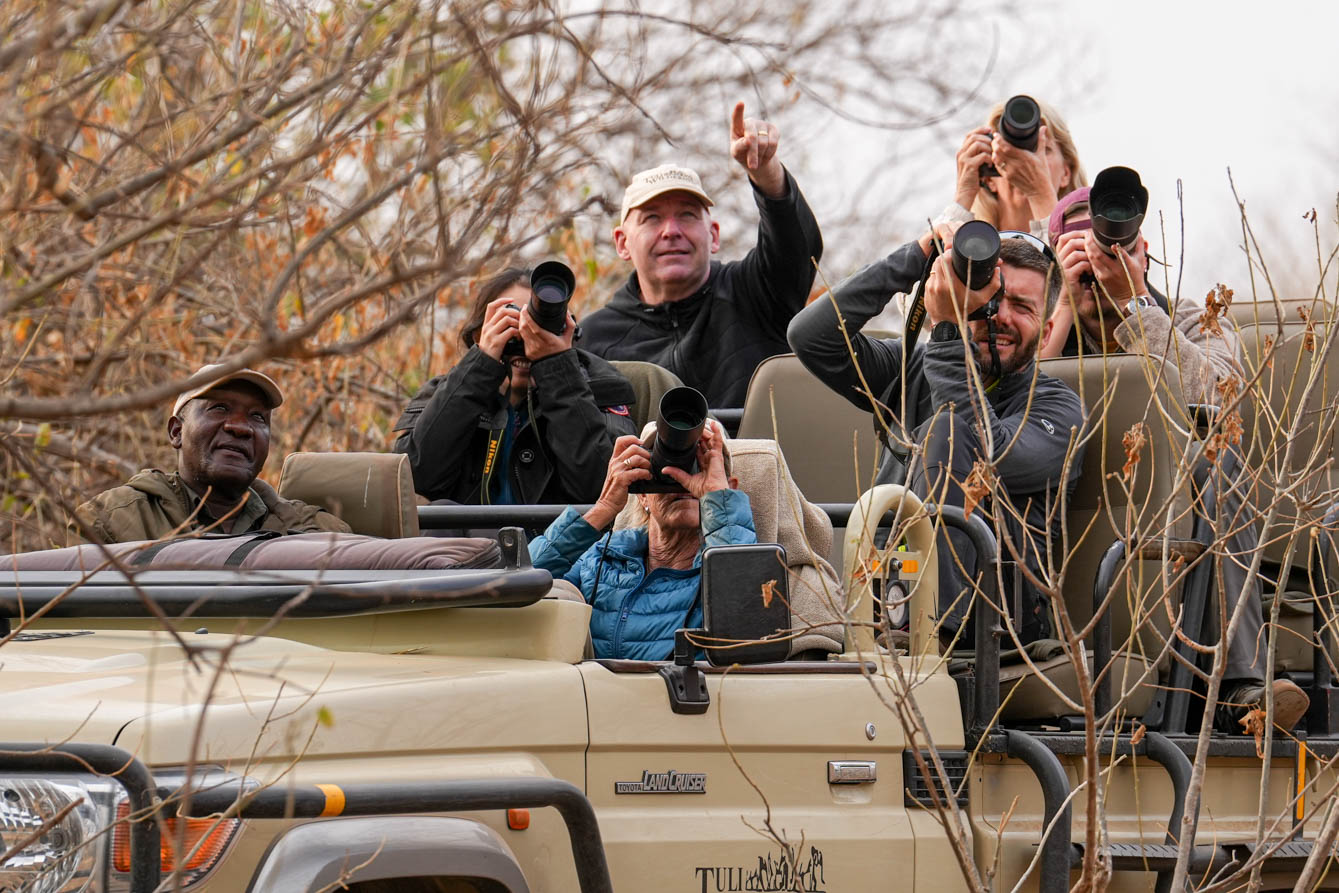 a group of photographers sitting on a vehicle while taking photos